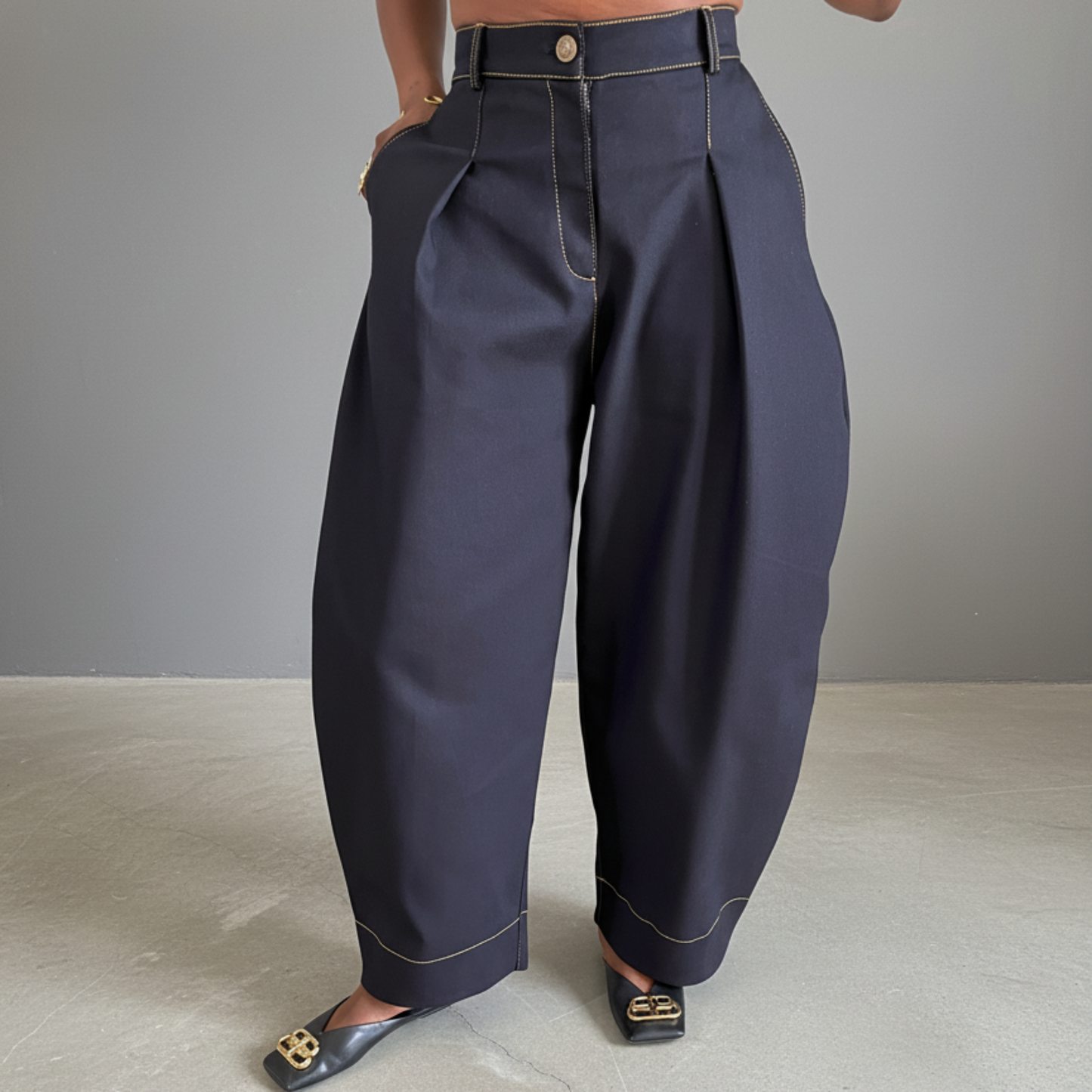 Person wearing dark blue high-waisted pants on a plain background