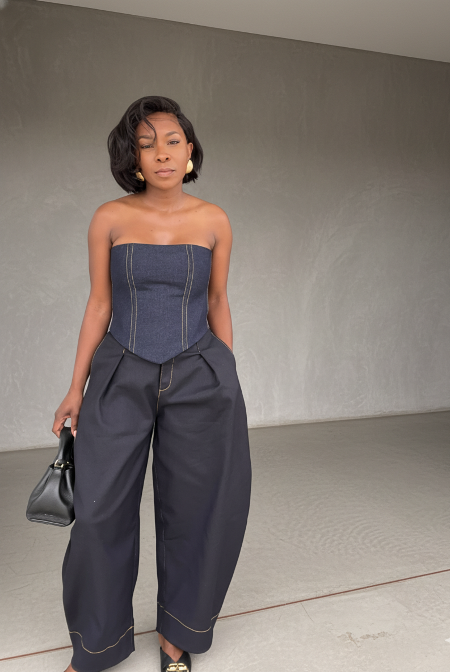 Woman wearing a strapless denim top and wide-leg jeans against a plain background