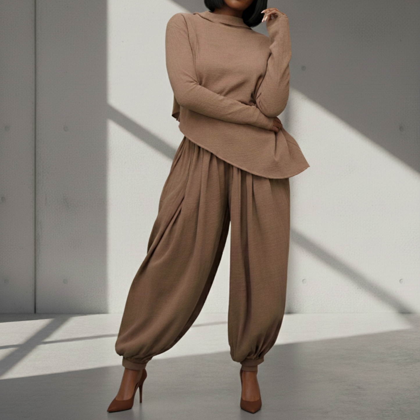 Woman wearing a brown outfit standing against a light gray wall.