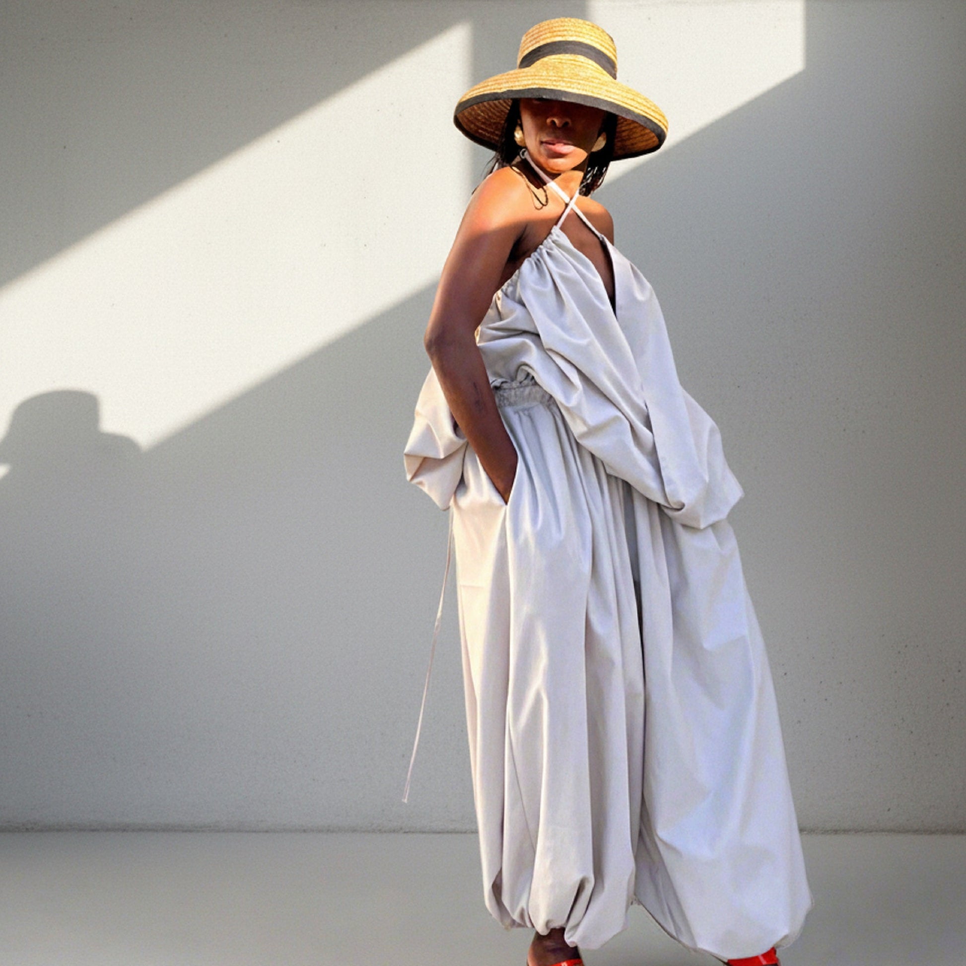 Woman wearing a white dress and straw hat in a sunlit room