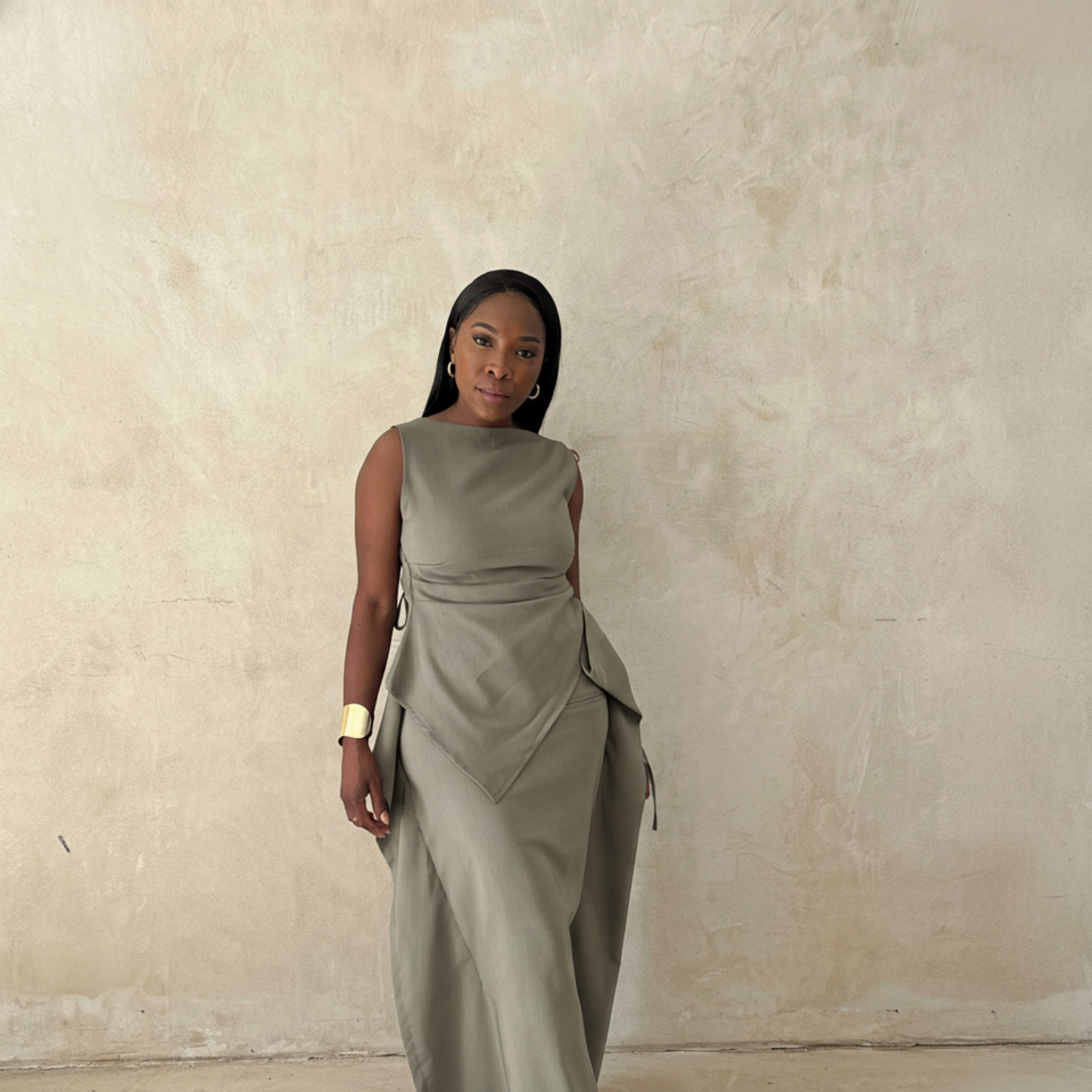 Woman wearing a gray dress against a beige wall