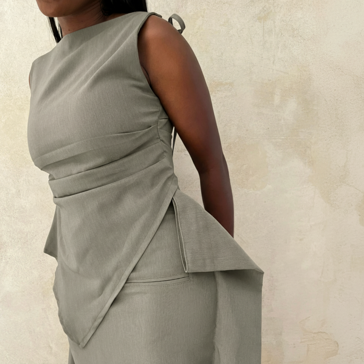 Woman wearing a gray sleeveless dress against a beige background